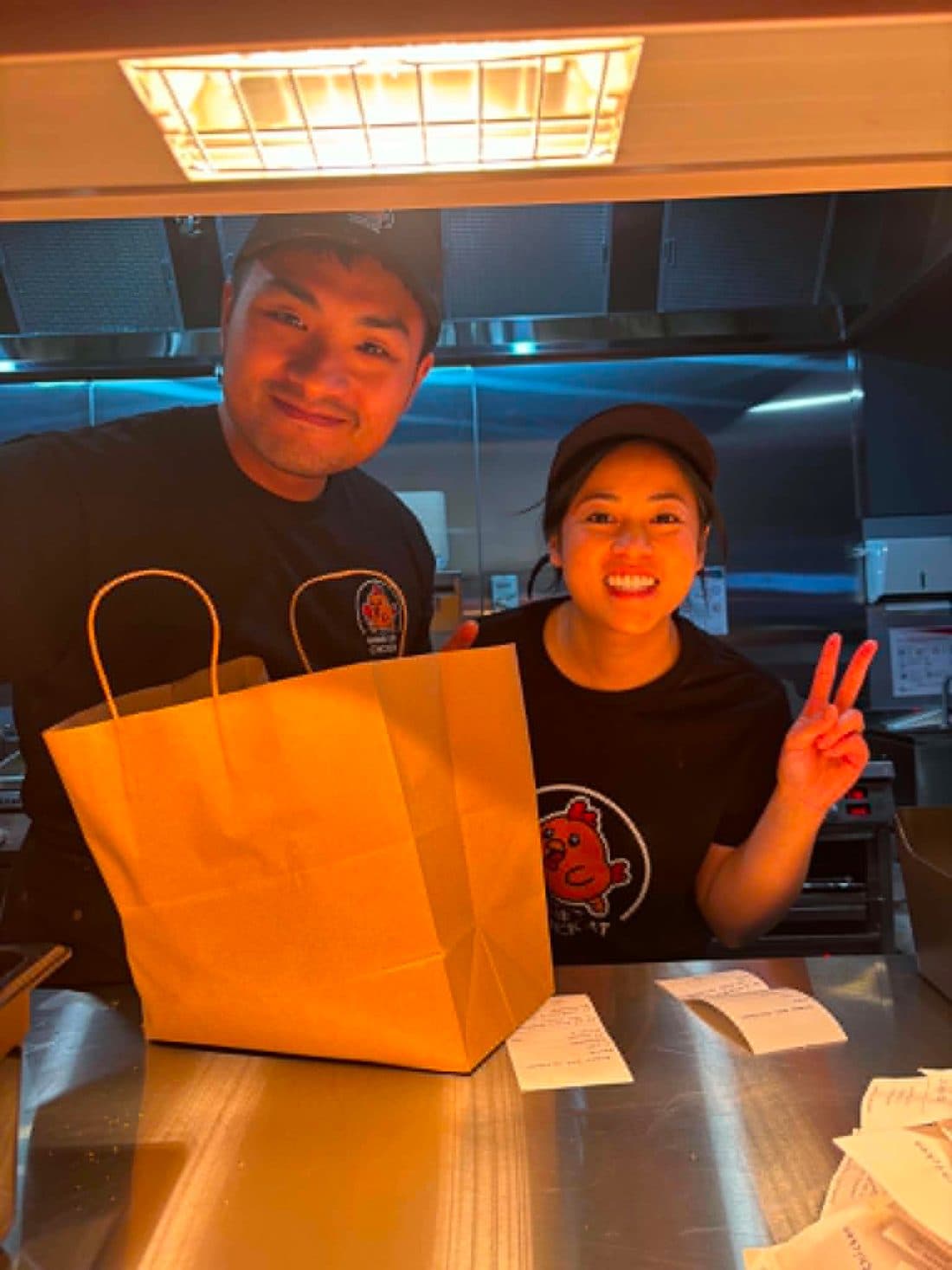 Two team members at the counter handing over a takeaway bag